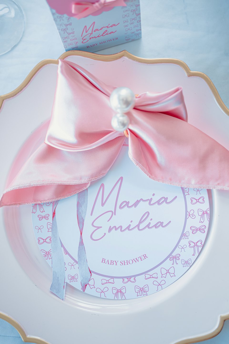 A decorative baby shower place setting featuring a pink satin bow.