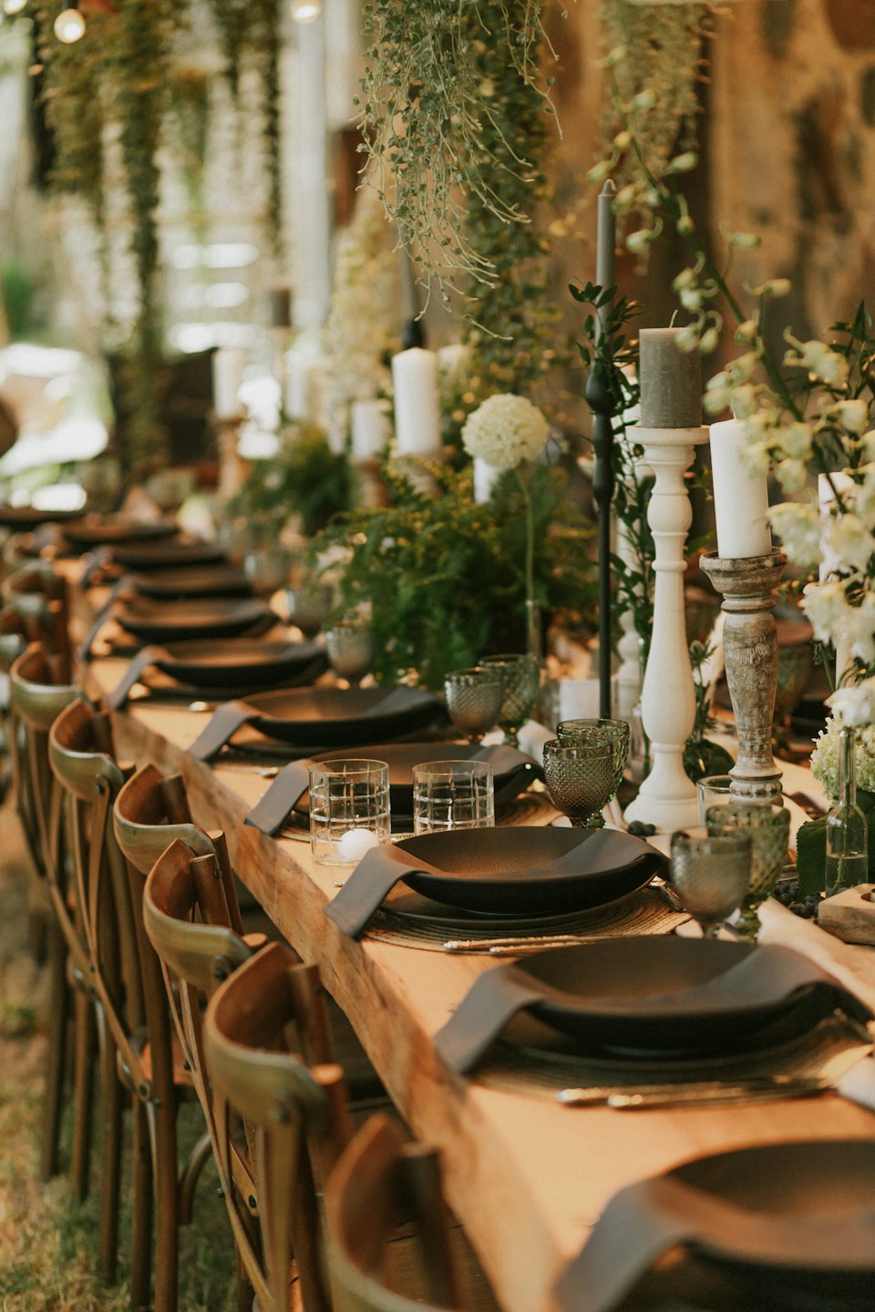 Rustic wooden table set for an event with candles and flowers.